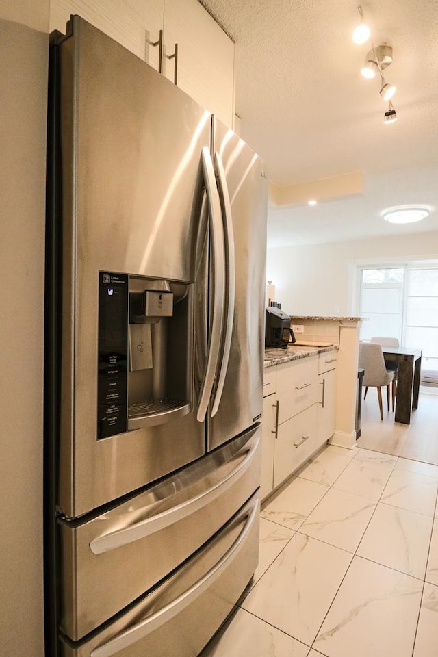 kitchen featuring light stone counters, marble finish floor, white cabinets, and stainless steel fridge with ice dispenser