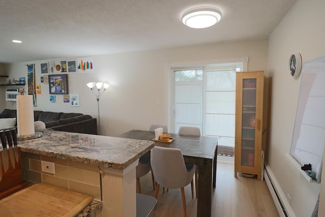 kitchen featuring a baseboard heating unit, light stone counters, and light wood-style floors