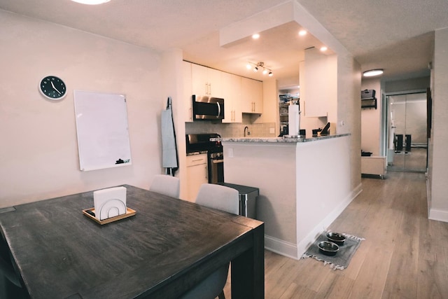 dining space with recessed lighting, baseboards, light wood finished floors, and track lighting