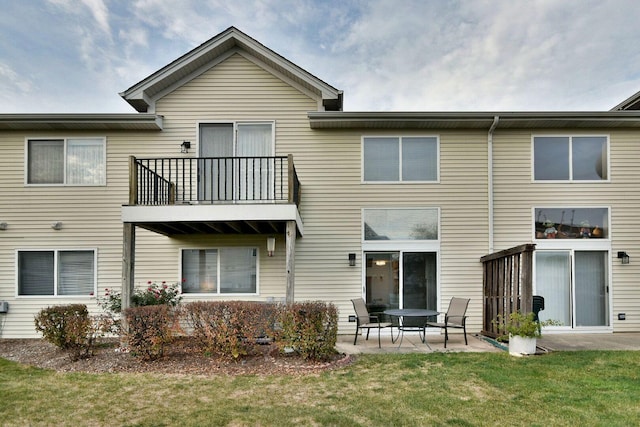 rear view of house featuring a lawn, a patio area, and a balcony