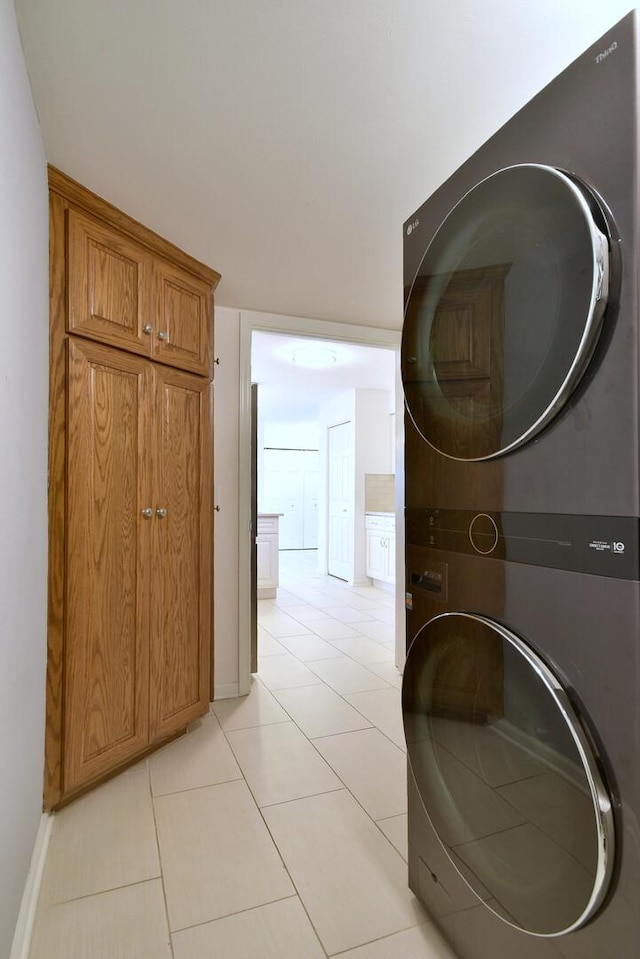 washroom with light tile patterned floors, baseboards, cabinet space, and stacked washer / dryer