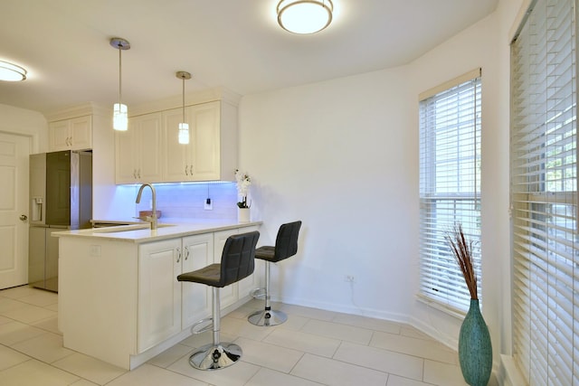 kitchen with hanging light fixtures, a sink, fridge with ice dispenser, light tile patterned floors, and a peninsula