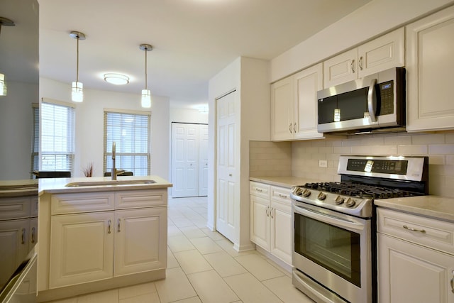 kitchen featuring light tile patterned floors, appliances with stainless steel finishes, a sink, and tasteful backsplash