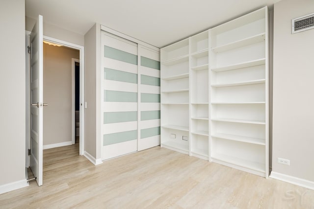 interior space featuring baseboards, light wood-type flooring, and visible vents