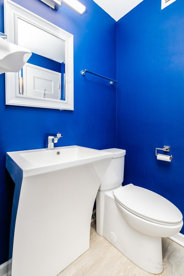 half bath with toilet and wood finished floors