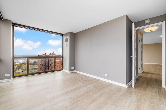 spare room featuring light wood-style floors, baseboards, and visible vents