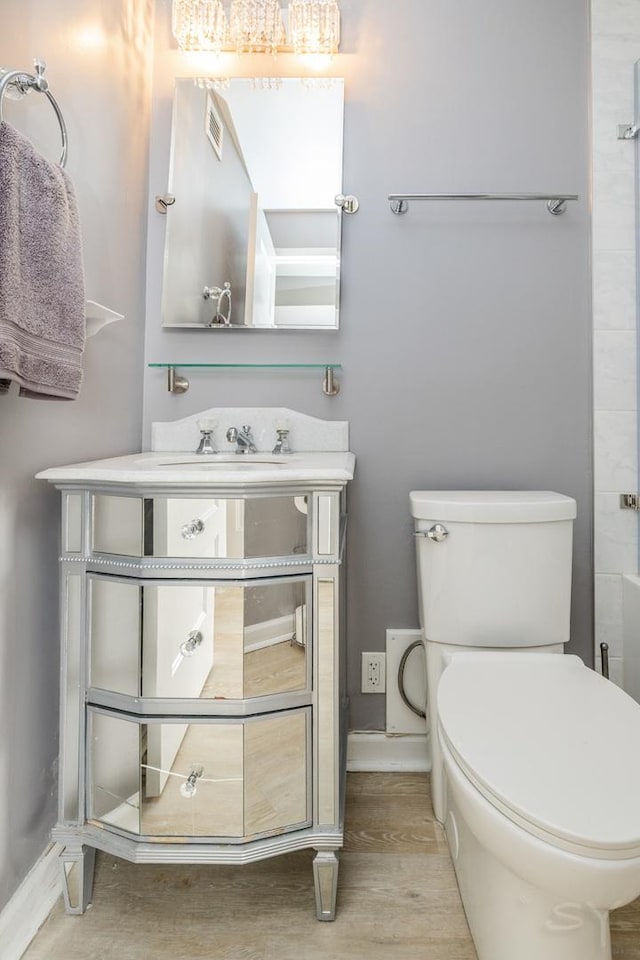 bathroom with toilet, baseboards, and vanity
