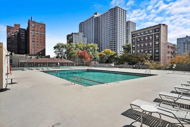 pool with fence, a view of city, and a patio