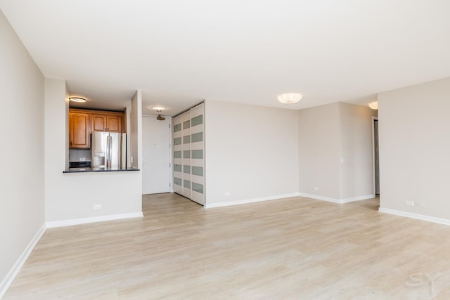 unfurnished living room with baseboards and light wood-type flooring