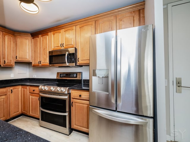 kitchen with dark stone counters and appliances with stainless steel finishes