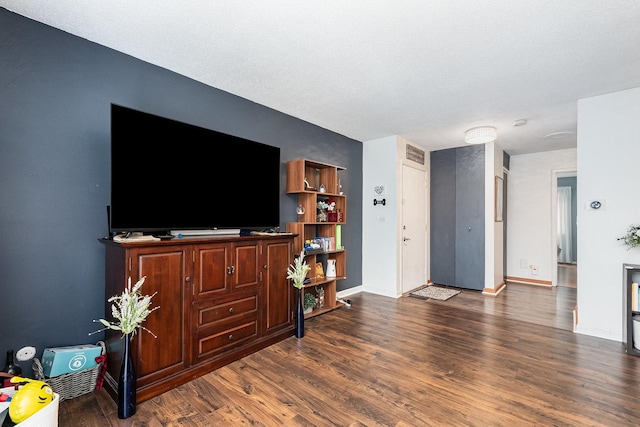 living room featuring baseboards, visible vents, and wood finished floors