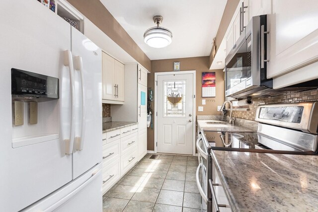 kitchen featuring decorative backsplash, light stone countertops, a sink, stainless steel appliances, and white cabinetry