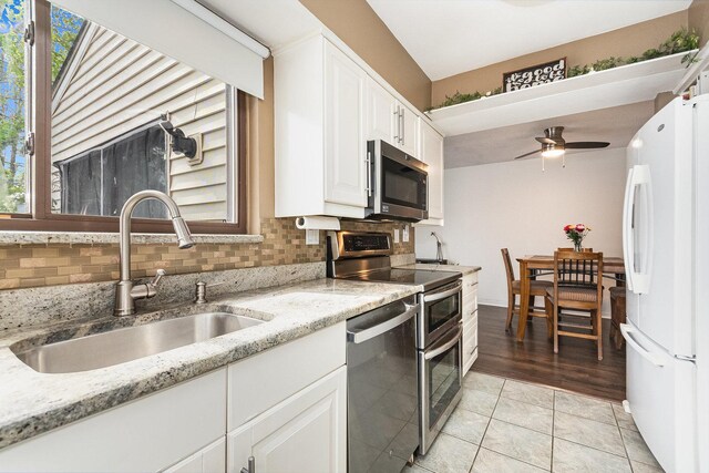 kitchen featuring a ceiling fan, white cabinets, tasteful backsplash, a sink, and stainless steel appliances