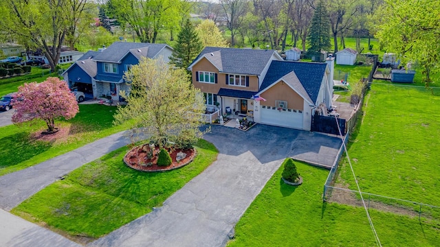view of front facade featuring a porch, driveway, a front yard, fence, and stucco siding