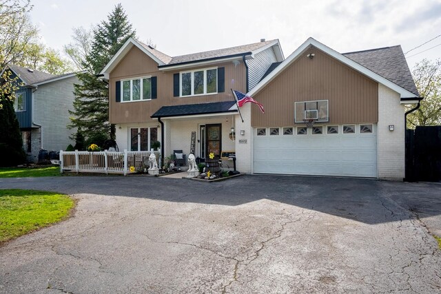 view of front of house featuring roof with shingles, an attached garage, brick siding, and aphalt driveway