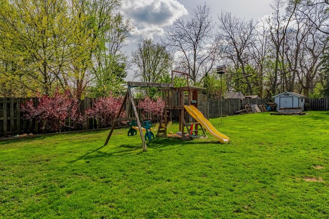 view of play area featuring a lawn, an outdoor structure, a fenced backyard, and a storage unit
