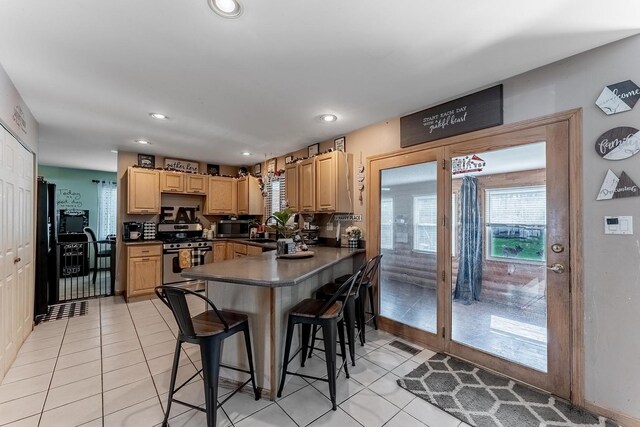 kitchen with stainless steel appliances, dark countertops, light tile patterned floors, and a kitchen bar