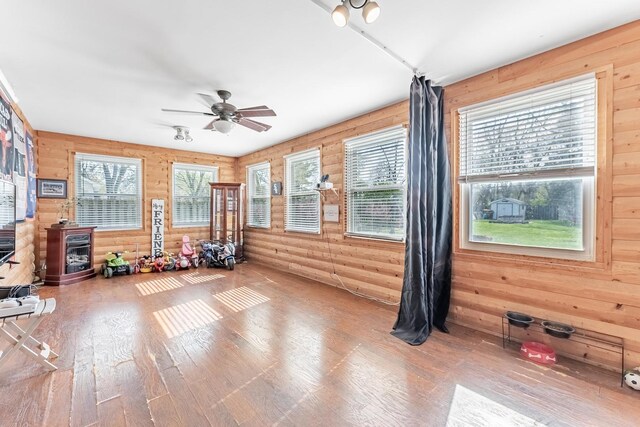interior space with wood walls, ceiling fan, and wood finished floors