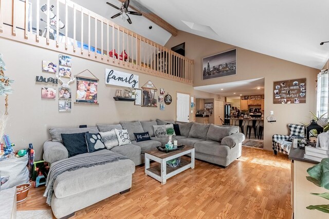living area with high vaulted ceiling, ceiling fan, beam ceiling, and light wood-style flooring