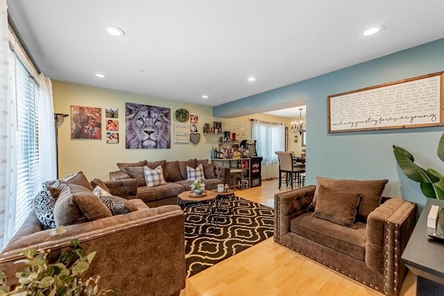 living room featuring plenty of natural light, recessed lighting, wood finished floors, and a notable chandelier