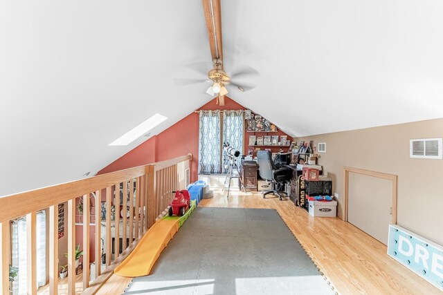 home office with vaulted ceiling with skylight, a ceiling fan, wood finished floors, and visible vents