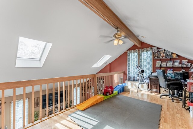 home office with vaulted ceiling with skylight, a ceiling fan, wood finished floors, and a wealth of natural light