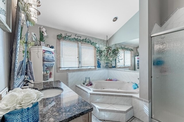 full bathroom with vaulted ceiling, vanity, a whirlpool tub, and a stall shower