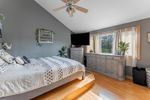 bedroom with a ceiling fan, vaulted ceiling, and light wood-style flooring