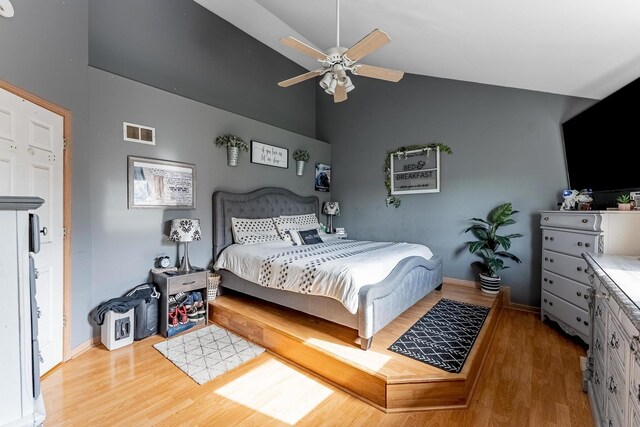 bedroom featuring visible vents, baseboards, wood finished floors, and high vaulted ceiling