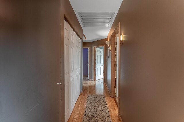 hallway featuring visible vents, light wood finished floors, and baseboards