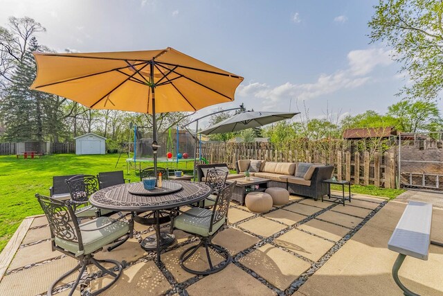 view of patio / terrace featuring an outdoor living space, a trampoline, a storage shed, an outbuilding, and a fenced backyard