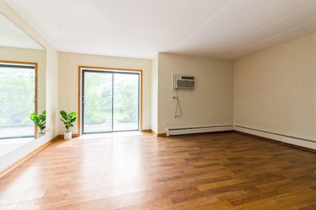 unfurnished room featuring baseboards, a baseboard heating unit, wood finished floors, and a wall mounted air conditioner