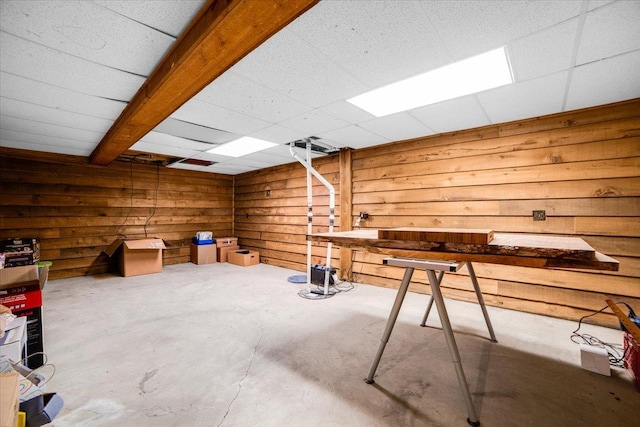 miscellaneous room featuring wood walls, concrete flooring, and a drop ceiling