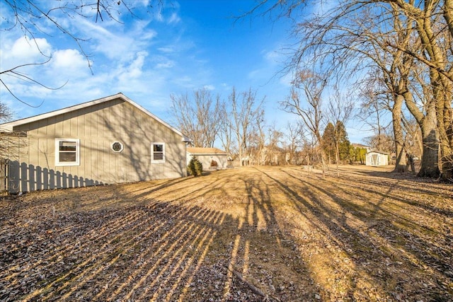 view of yard with fence, an outbuilding, and a shed