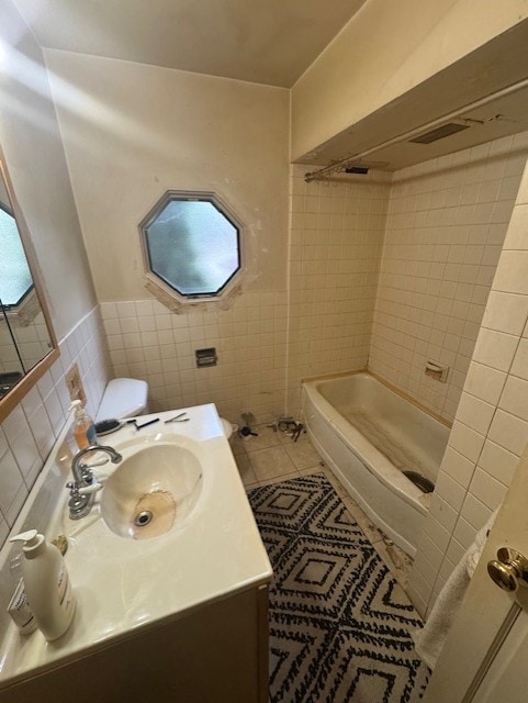 bathroom featuring vanity, tub / shower combination, tile walls, a wainscoted wall, and tile patterned floors