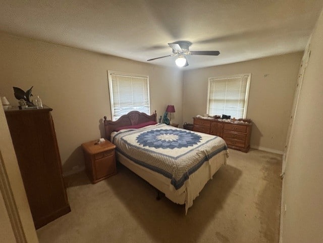 bedroom featuring a ceiling fan, light carpet, and multiple windows