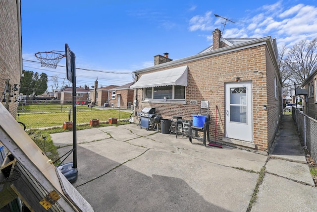 rear view of property featuring a yard, brick siding, a chimney, and a patio