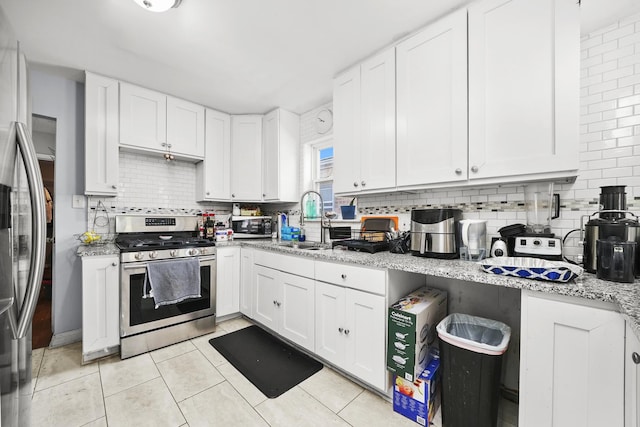 kitchen featuring backsplash, stainless steel appliances, white cabinetry, and a sink