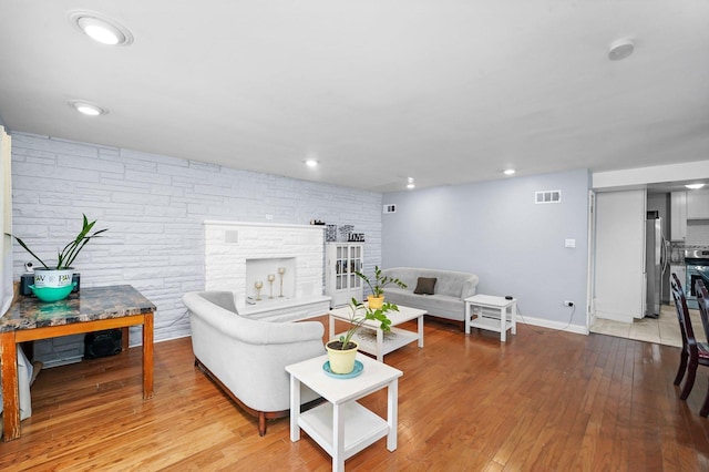 living room featuring visible vents, baseboards, a stone fireplace, recessed lighting, and hardwood / wood-style flooring
