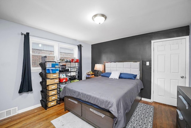 bedroom featuring baseboards, visible vents, and wood finished floors