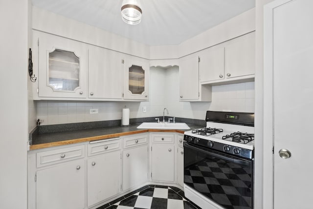 kitchen with range with gas cooktop, backsplash, a sink, white cabinets, and dark floors