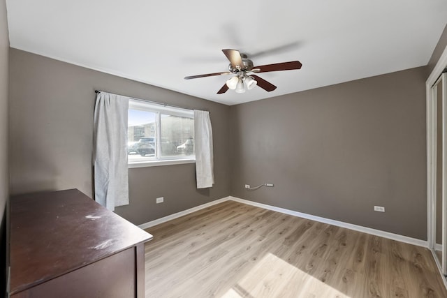 interior space featuring baseboards, a ceiling fan, and light wood-type flooring