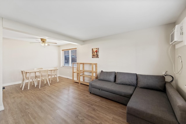 living area featuring baseboards, ceiling fan, wood finished floors, and a wall mounted air conditioner