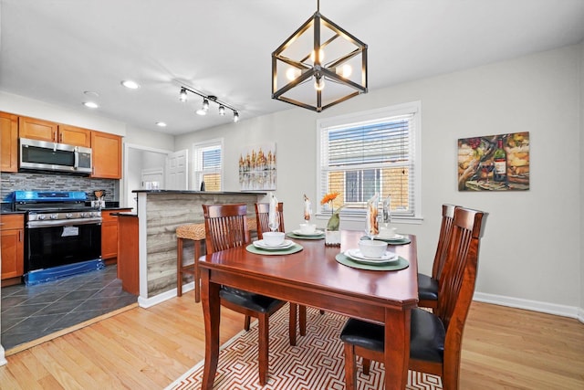 dining room with light wood-type flooring, recessed lighting, and baseboards
