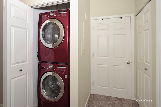 laundry room featuring laundry area, stacked washer and clothes dryer, baseboards, and carpet flooring