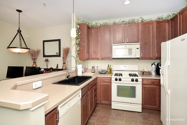 kitchen featuring pendant lighting, a sink, light countertops, a peninsula, and white appliances