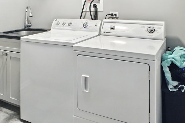 washroom with a sink, washer and clothes dryer, and cabinet space