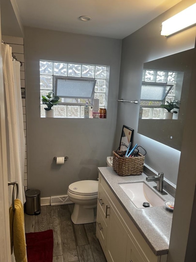 bathroom with toilet, baseboards, a shower with shower curtain, vanity, and wood finished floors