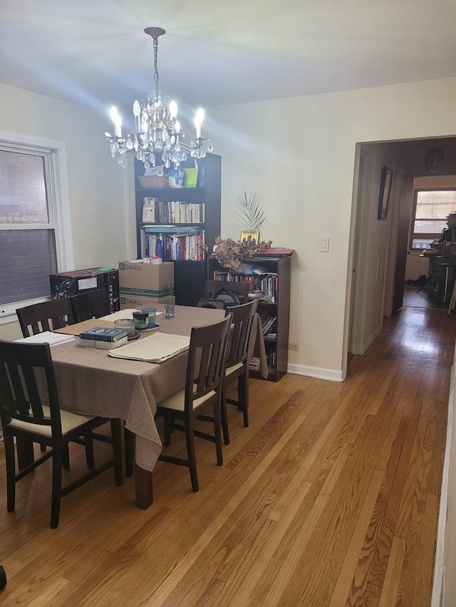 dining area featuring baseboards, a notable chandelier, and wood finished floors