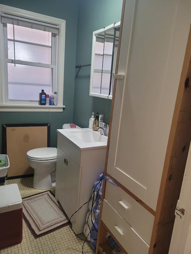 half bathroom featuring vanity, a healthy amount of sunlight, and toilet